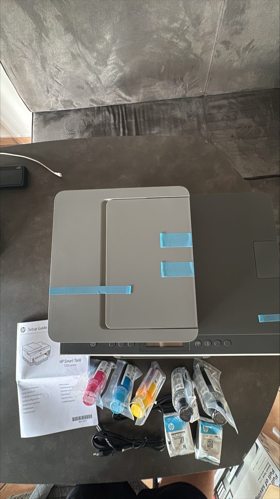 HP Smart Tank 7305 von oben mit blauem Transport-Klebeband und Tintenflaschen